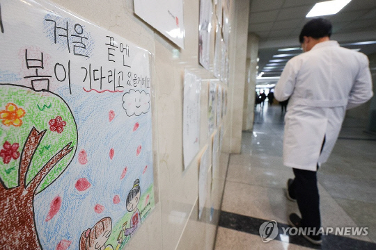 3일 대구의 한 대학병원에 붙은 글귀 옆으로 의료 관계자가 이동하고 있다. 연합뉴스